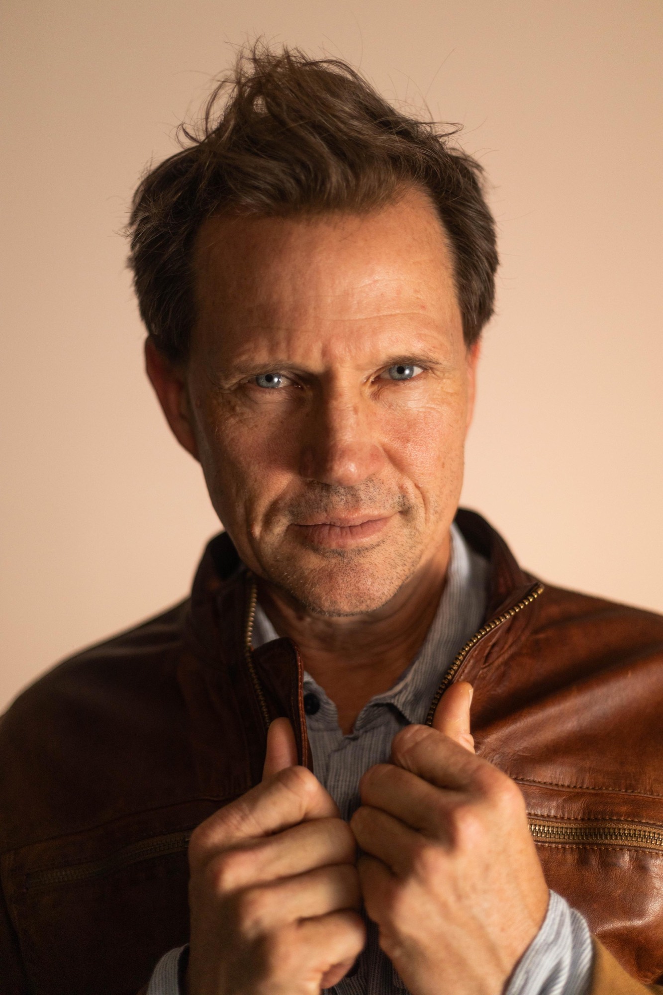 Langley Kirkwood, 2024 portrait in a brown leather jacket, looking straight at the camera.